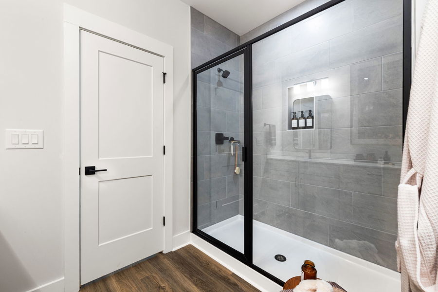 Tiled walk-in shower in a primary bathroom at HARMON Jefferson Village